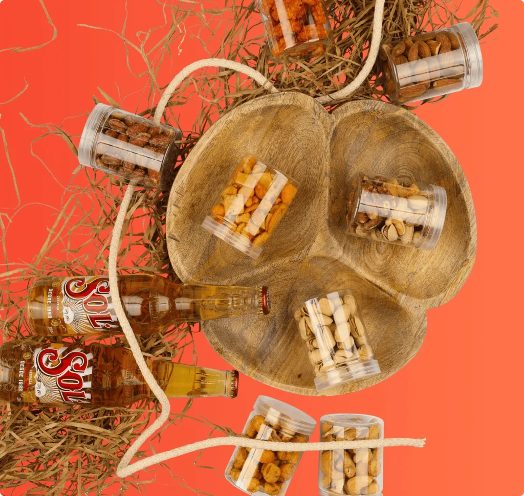 Assorted snack jars with two beer bottles displayed on a wooden tray against an orange background