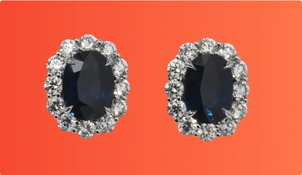 Pair of sapphire and diamond stud earrings displayed on an orange background